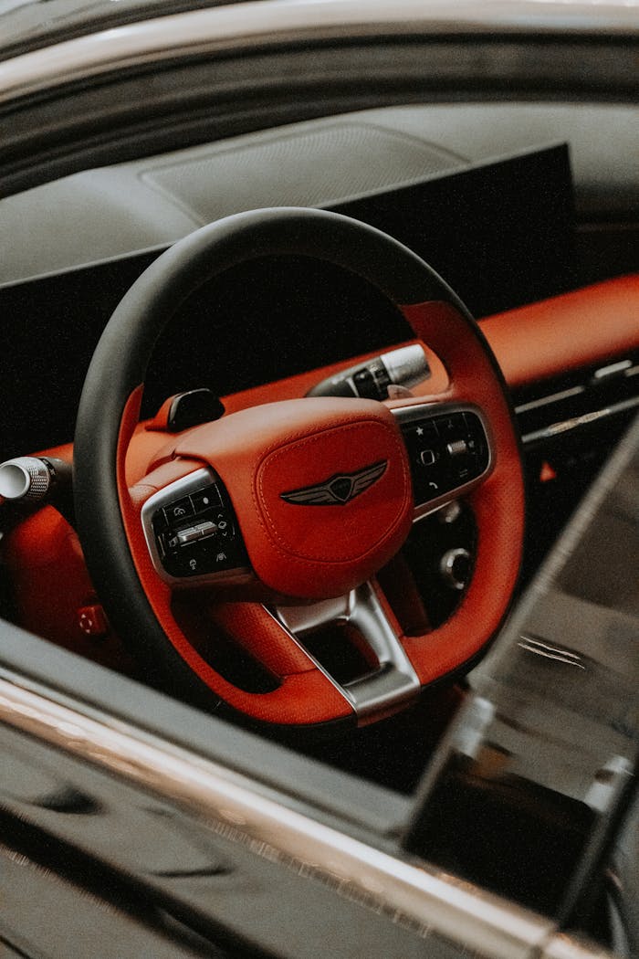 Close-up of a luxury car's interior featuring a red leather steering wheel. Modern and stylish design.